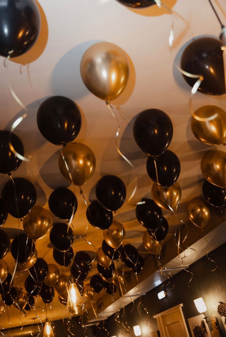 Zwarte en gouden ballonnen met linten tegen het plafond