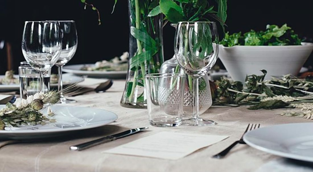 Sfeervolle detailstyling met glaswerk en groen op een besloten diner