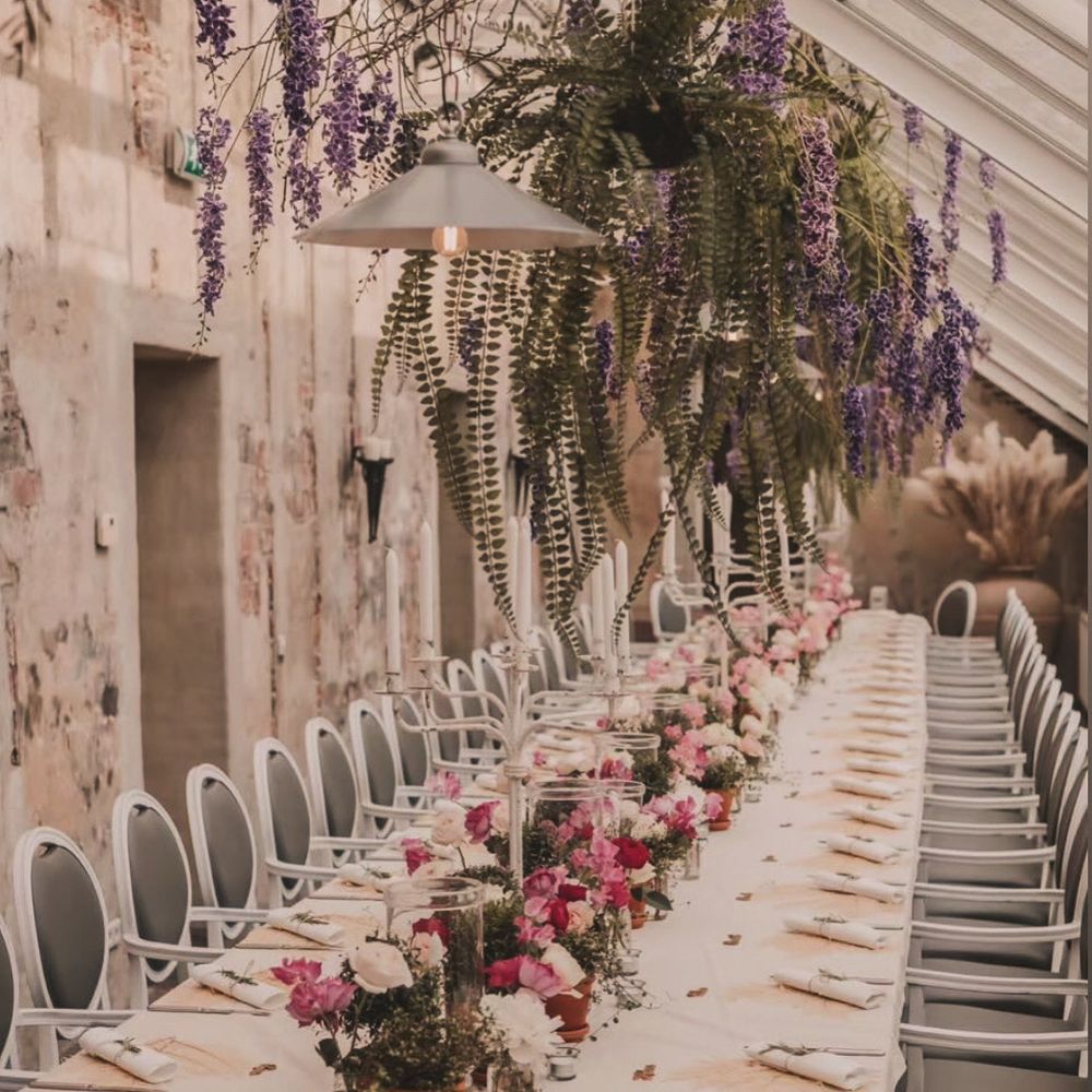 Lange dinertafel onder hangende paarse wisteria